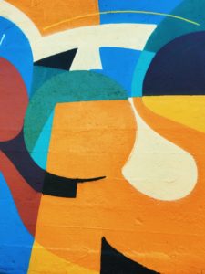 An abstract wall mural of organic circular and square shapes in orange, blue and red.